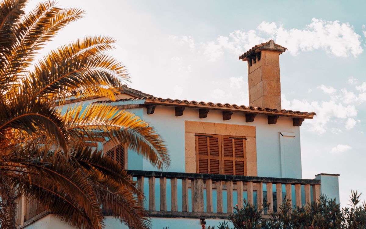 Casa mallorquina en Calvià con fachada encalada, contraventanas de madera, chimenea de piedra y cubierta de teja árabe